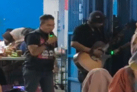 Udhin Leaders (kiri) saat ikut bernyanyi dengan seorang pengamen (kanan) yang menyanyikan lagu Salimu Naraka