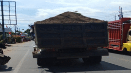Dump truk pengankut material bak terbuka di jalan poros gowa