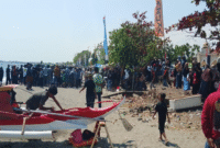 Warga yang memadati bibir pantai untuk menyaksikan ketangkasan para joki katinting menaklukkan ombak.