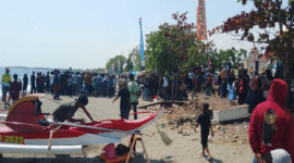Warga yang memadati bibir pantai untuk menyaksikan ketangkasan para joki katinting menaklukkan ombak.