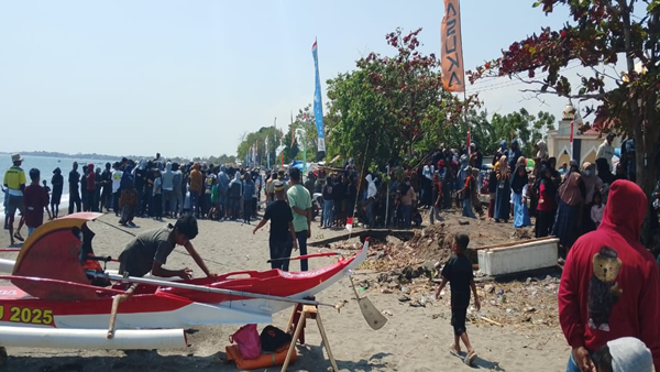Warga yang memadati bibir pantai untuk menyaksikan ketangkasan para joki katinting menaklukkan ombak.