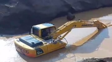 Excavator sedang mengeruk atau memindahkan material dari dasar genangan Milik H Ruppa
